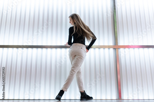 womens white velvet jeans, pants, black blouse, nubuck boots, a beautiful European model with long hair posing in the interior of the light panel