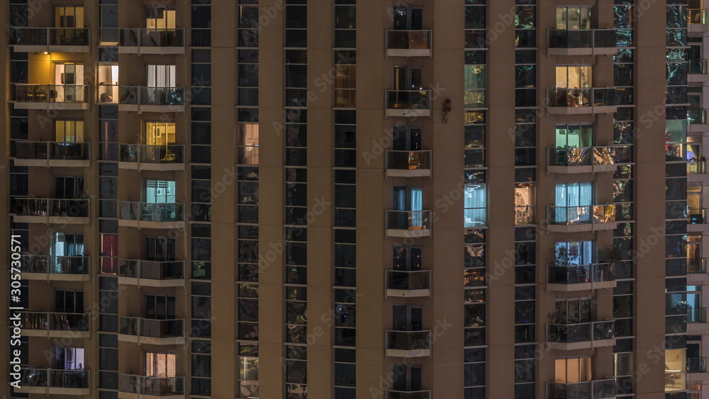 Rows of glowing windows with people in apartment building at night. Rows of glowing windows with people in apartment building at night.