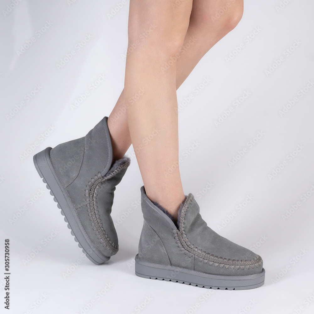Stylish womens soft warm winter boots with fur inside. Photo on legs of a model on a white background Stylish womens soft warm winter boots with fur inside. Photo on legs of a model on a white background