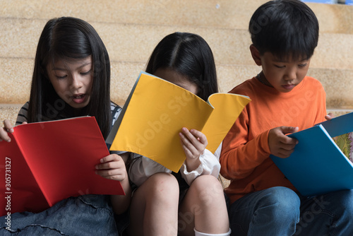 Three asian children,boy and girl siit on stair at school,reading book,fun and happy,education concept,learning and knowlage. photo