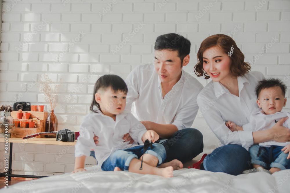Asian Japanese Family father mother son wearing white shirt hold guitar aculele posing photo on bedroom in white room.To keep memories moment cuteness of son in childhood lifestyle happy