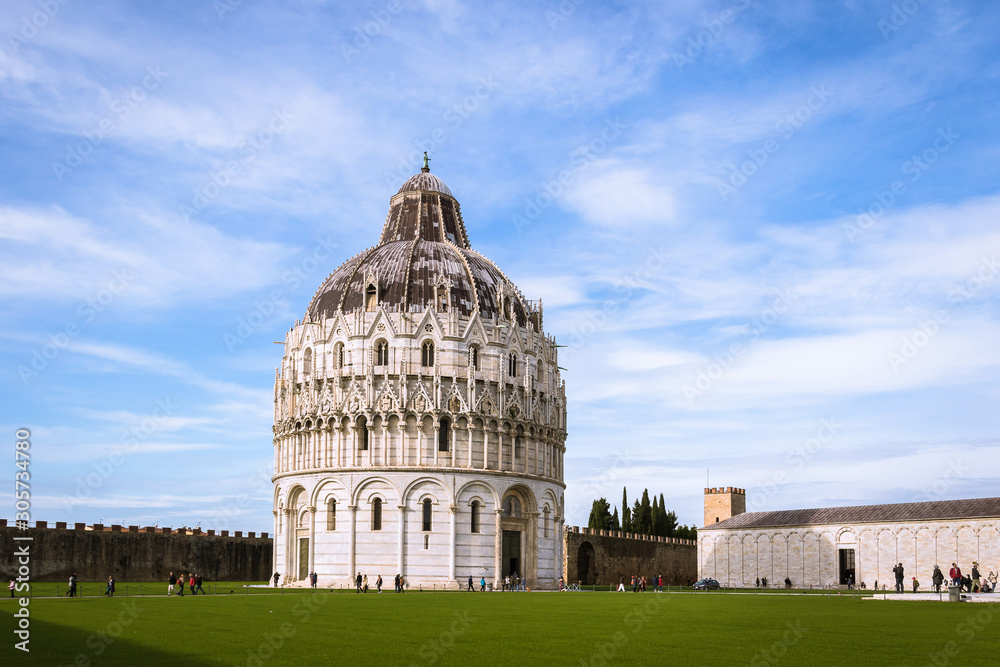 Square of Miracles with building of: the Baptistery which represents birth,  on the green grass under the lue sky in Pisa Tuscany in Italy.