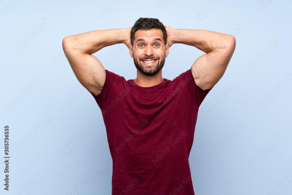 Handsome man over isolated blue background frustrated and takes hands on head