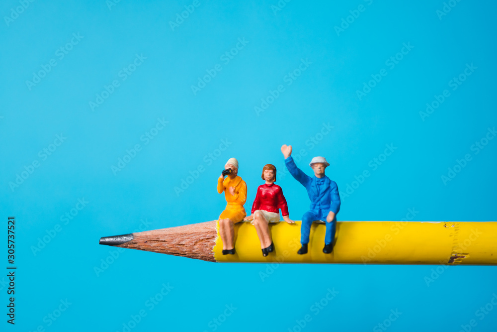 Miniature people, man and woman sitting on yellow pencil using as business and social concept