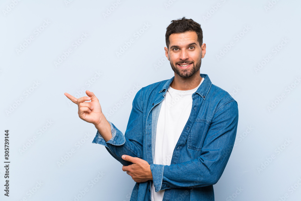 Handsome man over isolated blue background pointing finger to the side Handsome man over isolated blue background pointing finger to the side
