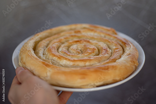 Foto Spiral-shaped Greek Cheese pie (Kichi Kozanis) in female hand, close up view