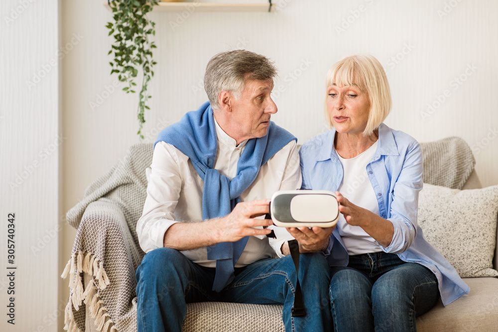 Modern senior couple testing VR glasses device