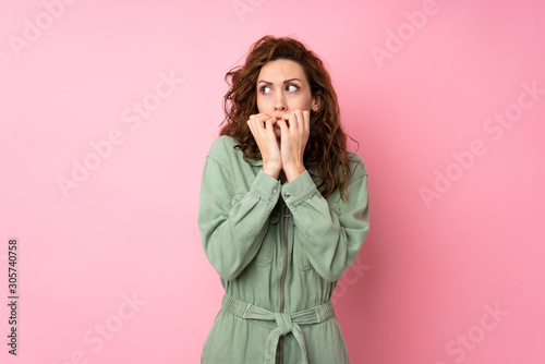 Young pretty woman over isolated pink background nervous and scared putting hands to mouth