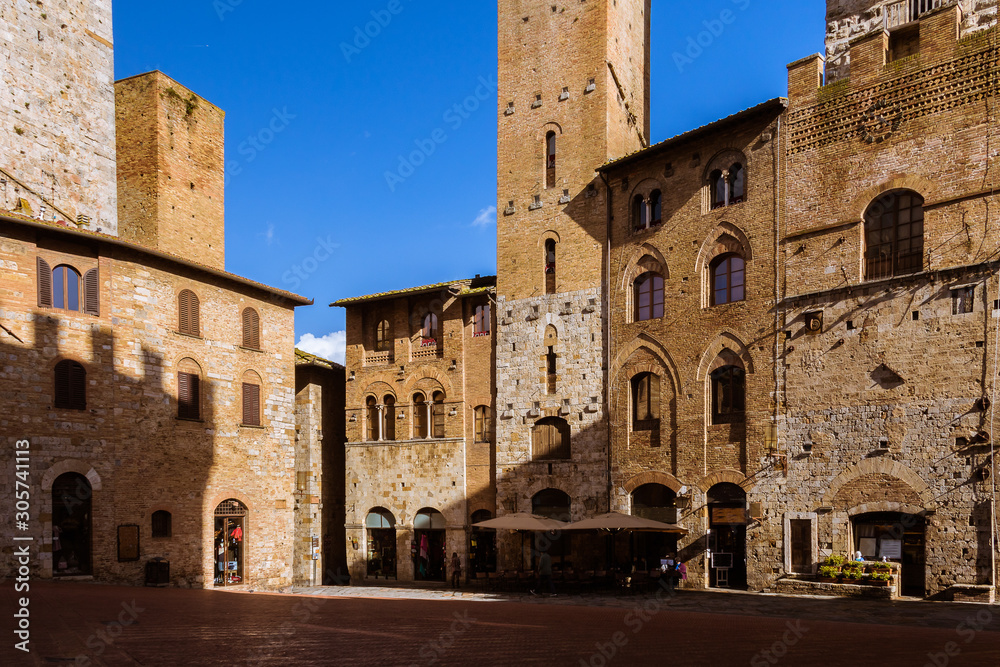 Medieval architecture with brick buildings in a small town in Tuscany, Italy under the blue sky. Light and shadow.. San Gimignano.