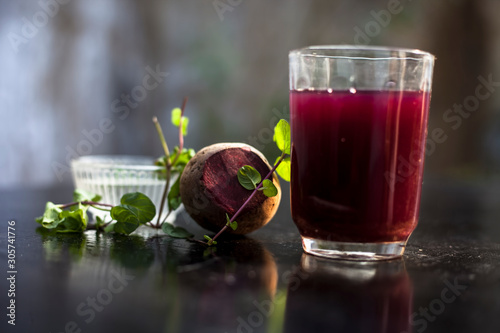 Beetroot smoothie in a glass on black glossy surface with some fresh mint leaves and water.Horizontal shot of beetroot smoothie along with some mint leaves. Shot with blurred background. photo