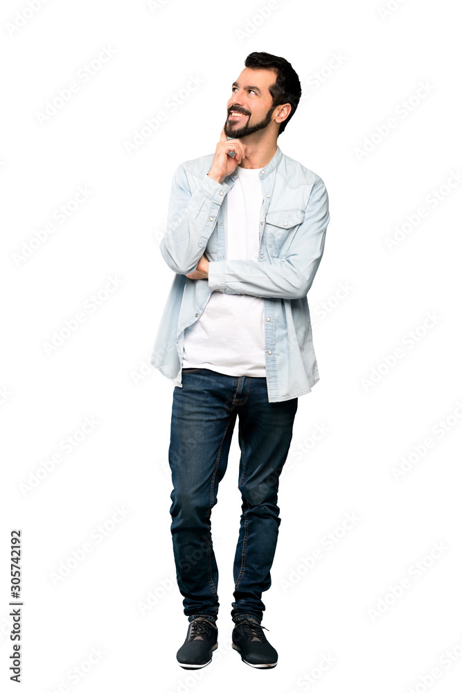Full-length shot of Handsome man with beard thinking an idea while looking up over isolated white background Full-length shot of Handsome man with beard thinking an idea while looking up over isolated white background