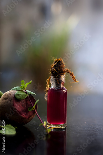 Fresh raw sliced beetroot along with some mint leaves and its extracted detoxifying essential oil in a tiny glass bottle.Vertical shot with blurred background. photo