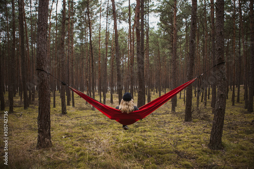 Woman relaxing in the hammock hanging among the pine trees in the background.