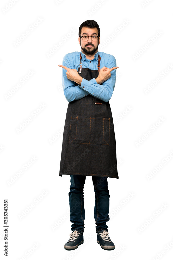 Full-length shot of Man with apron pointing to the laterals having doubts over isolated white background Full-length shot of Man with apron pointing to the laterals having doubts over isolated white background