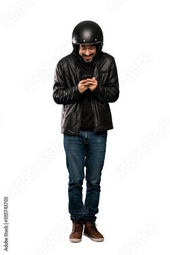 Full-length shot of Biker man surprised and sending a message over isolated white background © luismolinero