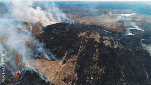 Forest and field fire. Dry grass burns, natural disaster. Aerial view. Large field fire with many places of burning.