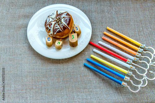 Festive donuts, menorah with color candles and dreidels are traditional symbo...
