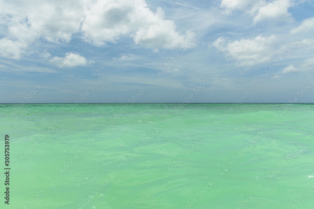 Amazing view of turquoise water of Atlantic ocean and blue sky with white clouds. Aruba Island. Beautiful nature background.