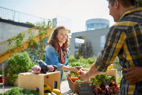 Friendly woman tending an organic vegetable stall at a farmer's