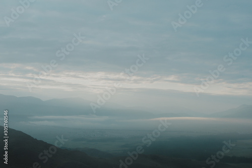 Gentle hills in bluish haze. Soft light in early morning, silhouettes of mountains