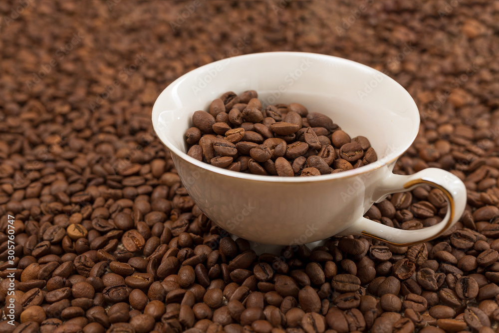 a cup with coffee grains is immersed in a scattering of other beans a cup with coffee grains is immersed in a scattering of other beans