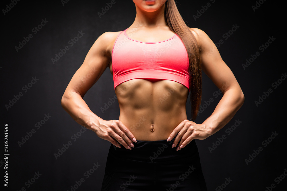 Close up of fit woman's torso with perfect abdomen muscles on black background