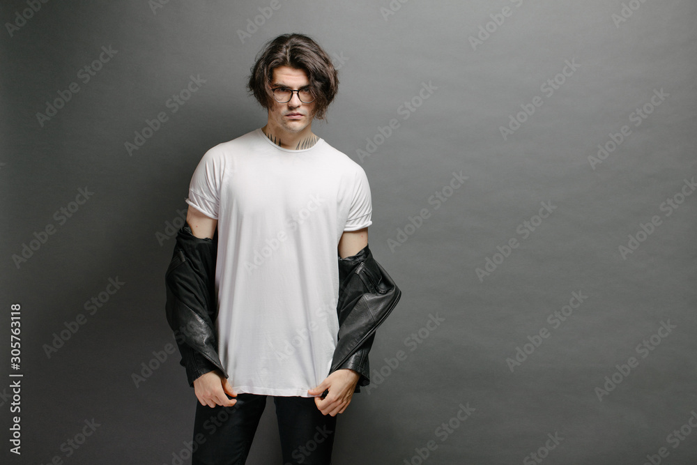 Hipster handsome male model with glasses wearing white blank t-shirt and black jeans with space for your logo or design in casual urban style - obrazy, fototapety, plakaty 