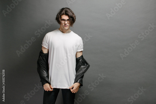 Hipster handsome male model with glasses wearing white blank t-shirt and black jeans with space for your logo or design in casual urban style