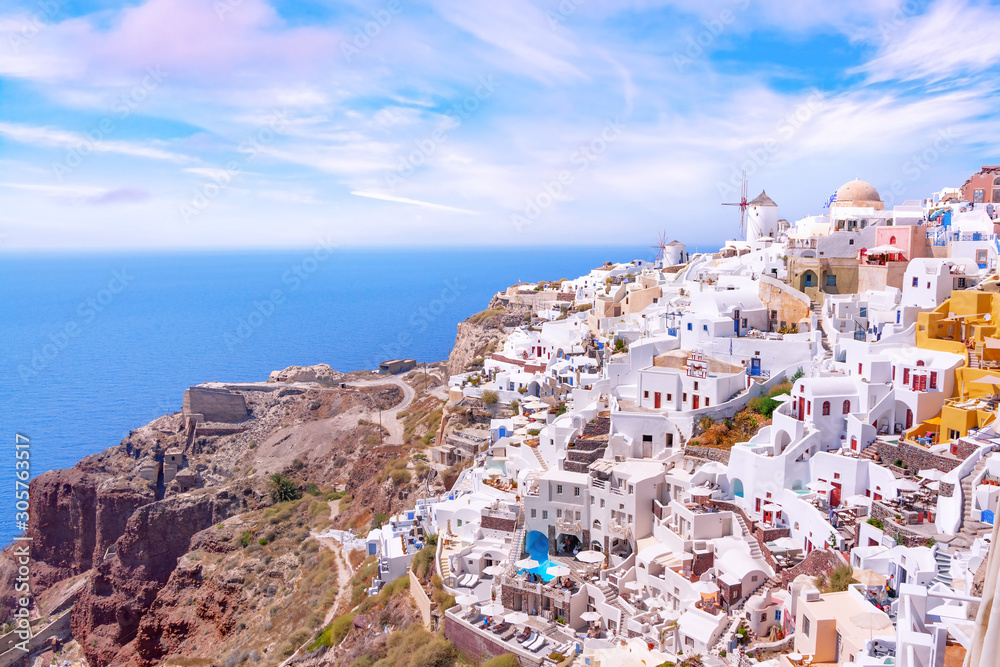 Beautiful view of picturesque village of Oia with traditional white architecture  and windmills in Santorini island in Aegean sea, Greece. Scenic travel background.