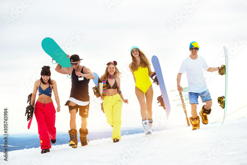 Happy friends snowboarders at ski resort in swimsuits