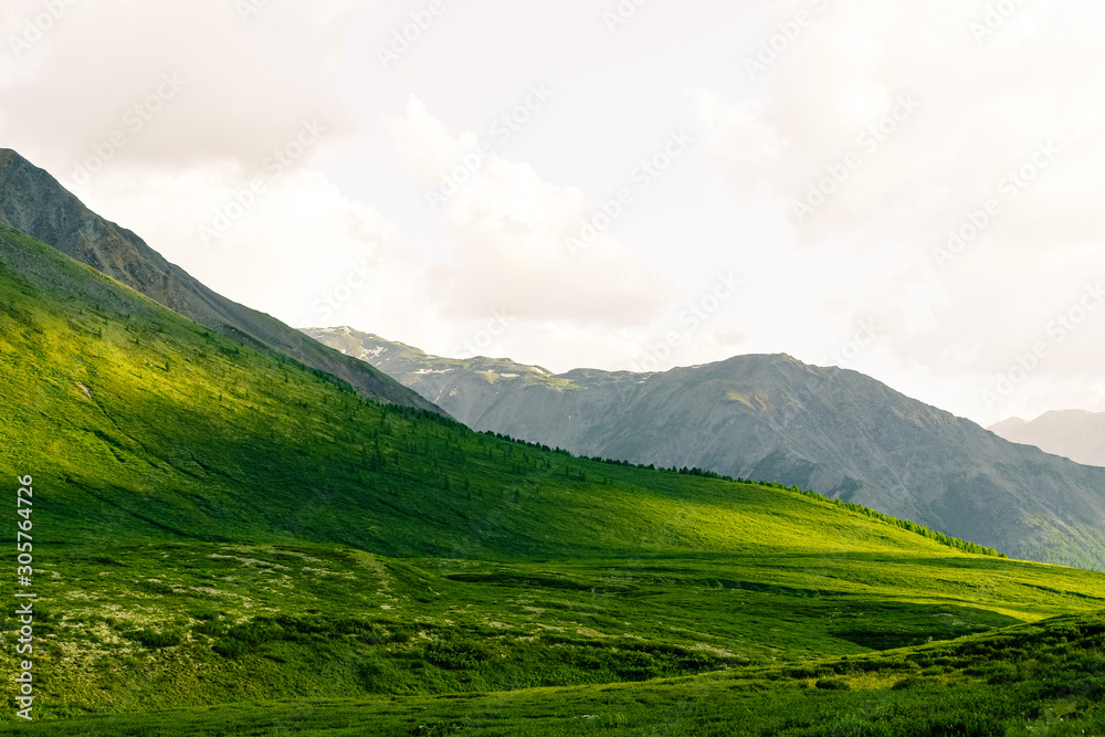 Soft hills with green grass under cloudy sky