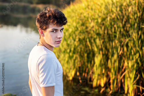 Portrait of a boy in a white T-shirt on a background of autumn nature. The guy often runs alone and with the company and plays sports in nature