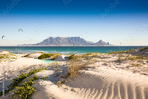 Fototapeta Naklejka Na Ścianę i Meble -  Beach dunes and kite surfers at Blouberg beach with in the background Cape Town and Table Mountain