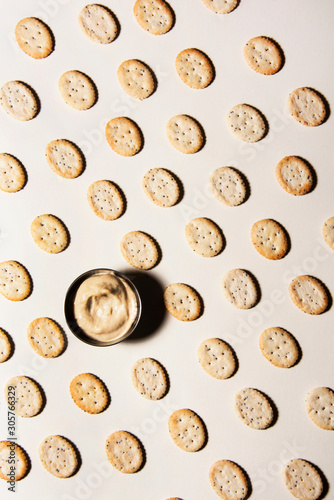 Salted cracker coins in a line with hummus sauce. Abstract food conception.