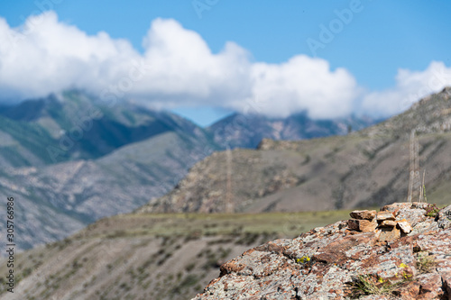 Ridge under the sky with clouds. Rocks with snow slopes, mountain landscape. Cross country tourist trip