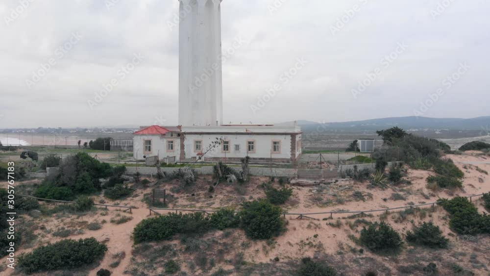 Aerial shot of Trafalgar lighthouse in Spain near the ocean. Cloudy sky and valley at the background. Drone raiseis up, no people. 4k (UHD) Aerial shot of Trafalgar lighthouse in Spain near the ocean. Cloudy sky and valley at the background. Drone raiseis up, no people. 4k (UHD)