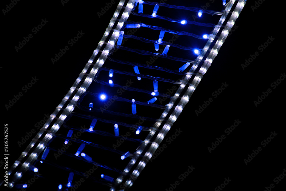 Part of Christmas decorative blue and white flashing lights, close up. Street detail of New Year and Christmas decorations, string rice lights bulbs. Ornaments to christmas celebration, holiday scene.