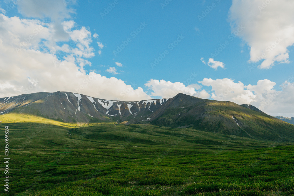 Fototapeta premium Green hills under blue cloudy sky. Mountain valley for pasture