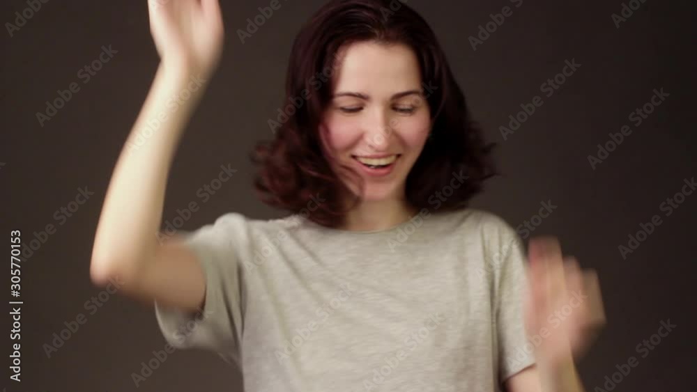 Cheerful brunette girl on dark background of empty Studio dancing and gesticulating