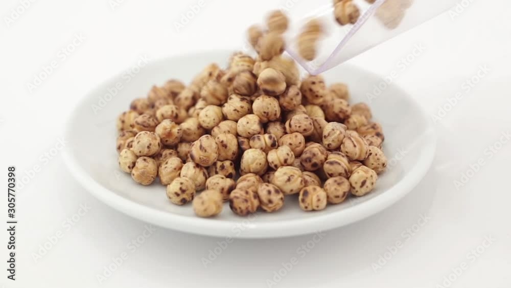 Roasted chickpea grains spilling on a rotating plate on a white background Roasted chickpea grains spilling on a rotating plate on a white background