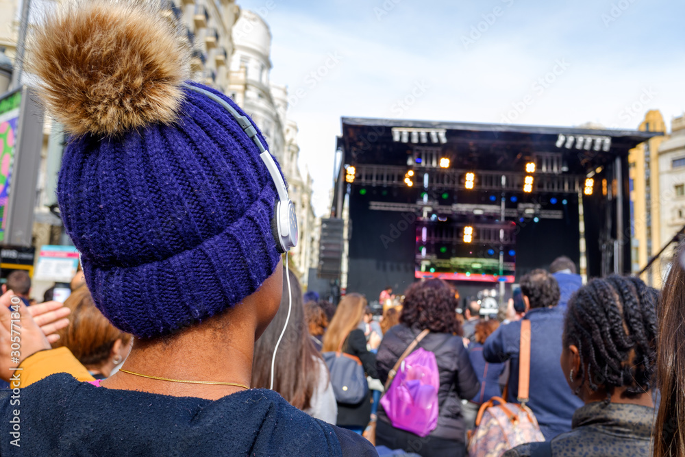 Young black woman enjoying listening to a live concert with headphones on her back.