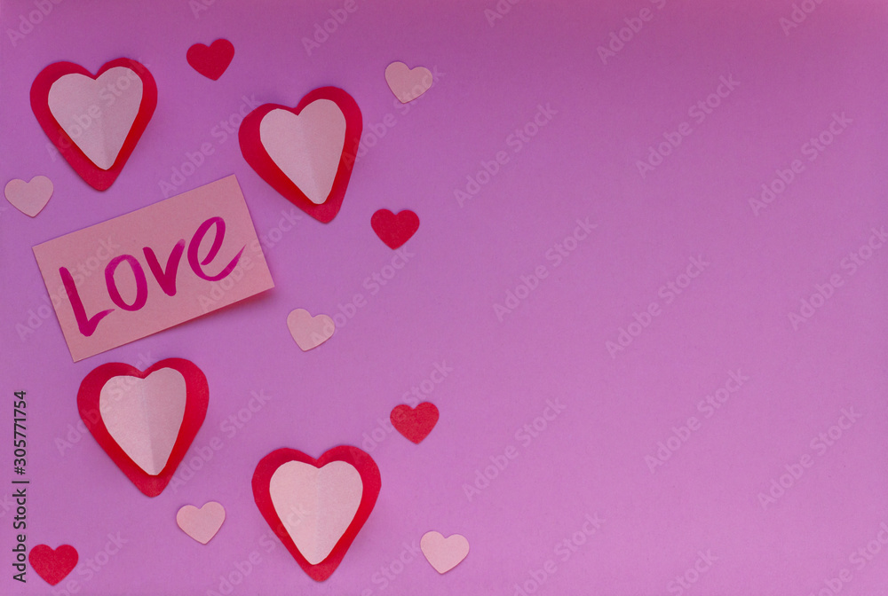 There are many red and pink hearts on the purple background. Valentin's Day, top view. 