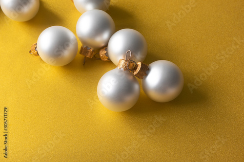 Christmas matt pearl color balls on shiny golden background with copy space. Modern New Year decoration, horizontal