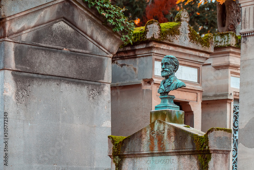 Stone bust in the most famous cemetery of Paris Pere Lachaise, France. Tombs of various famous people. Golden autumn over eldest tombs. photo