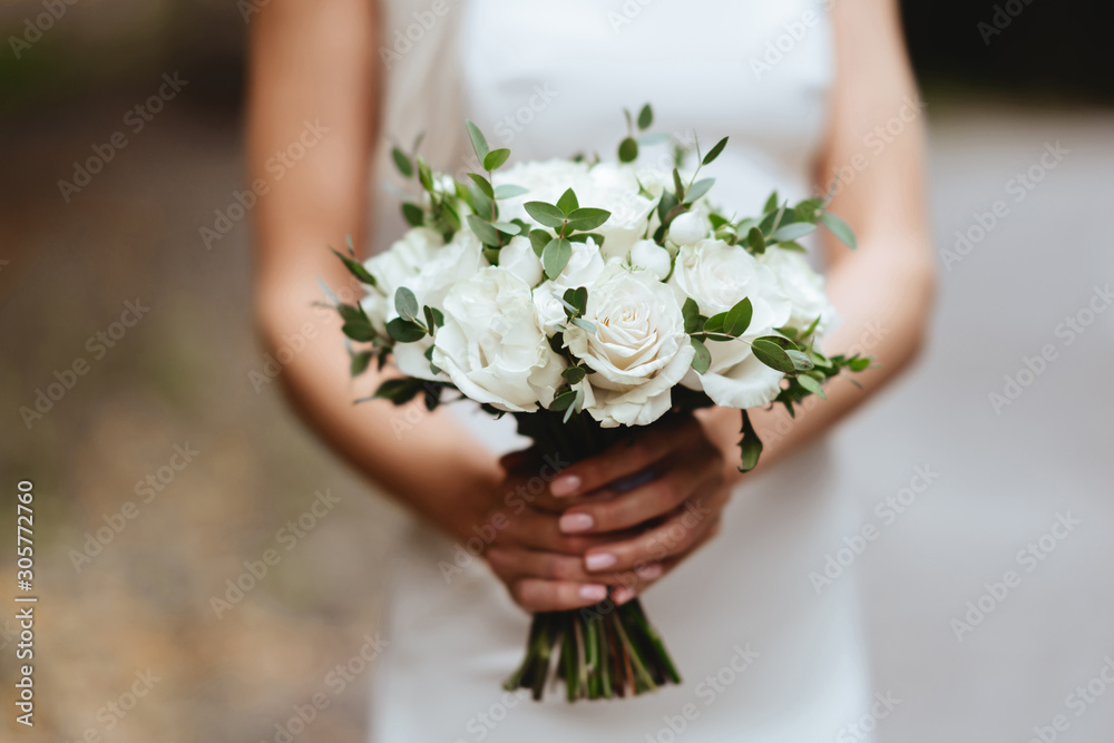 the bride is holding a wedding bouquet from white roses and eustoma the bride is holding a wedding bouquet from white roses and eustoma