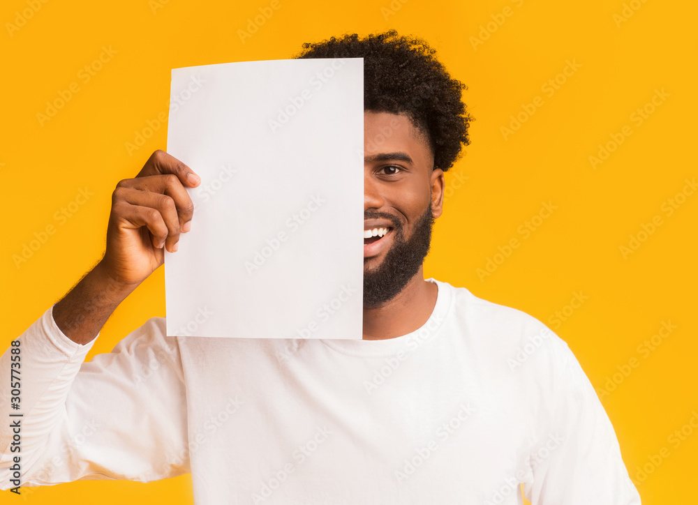 Smiling black guy covering half of his face with paper Smiling black guy covering half of his face with paper