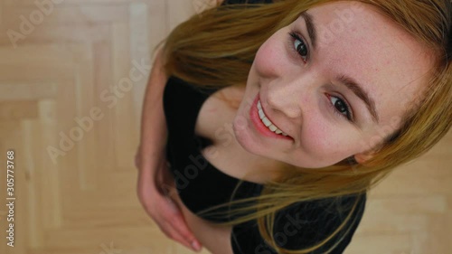 Overhead view of young woman standing with smile and looking to the camera.