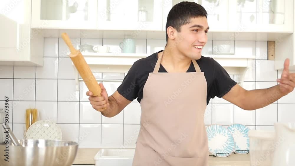 Handsome young caucasian funny man dancing in the kitchen at home in the morning and having fun on holidays Handsome young caucasian funny man dancing in the kitchen at home in the morning and having fun on holidays