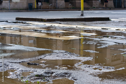 Obraz na plátně deteriorated and damaged road with puddles in the center of Milan, Italy
