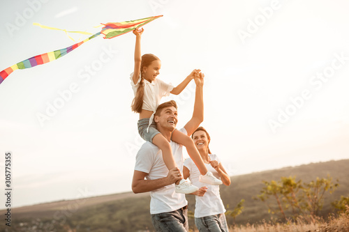 Happy family playing with kite in nature
